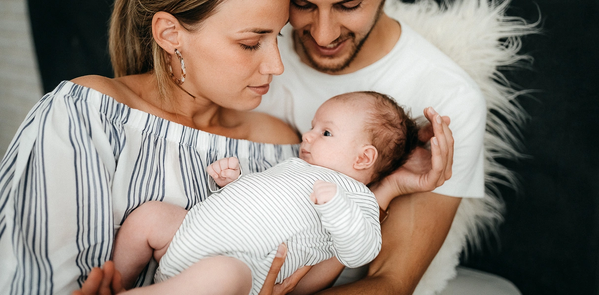 Pareja feliz sosteniendo a un bebé recién nacido tras un tratamiento de FIV exitoso